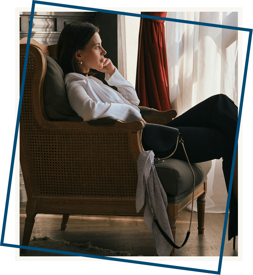 Woman sitting on chair looking out window reflecting on intrusive thoughts before starting OCD therapy in Atlanta Georgia