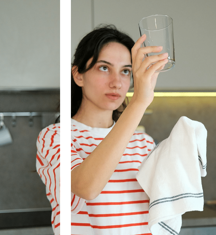 Woman washing glass checking water demonstrating contamination OCD ritual addressed in therapy sessions Atlanta Chamblee