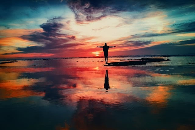 Person standing with arms open at sunset representing emotional relief and progress through anxiety therapy