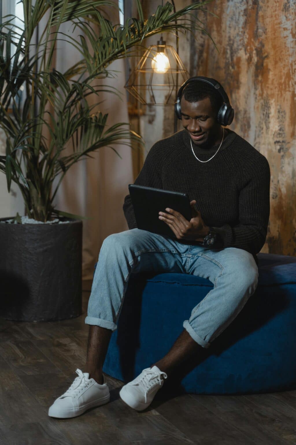 African American man using a tablet with headphones on, slight smile suggesting engagement, learning, or virtual support