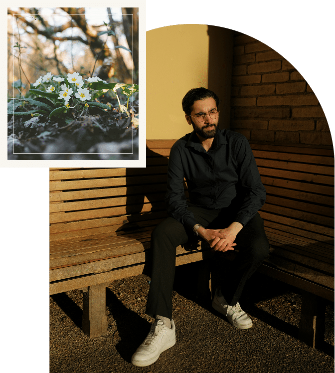 A man sitting on a bench with sunlight on his face, relaxed posture suggesting ease and reflection