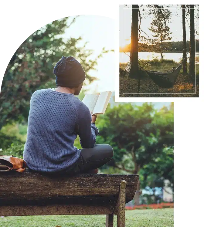 Man sitting on a bench in front of a peaceful nature scene, reading a book in a moment of quiet reflection