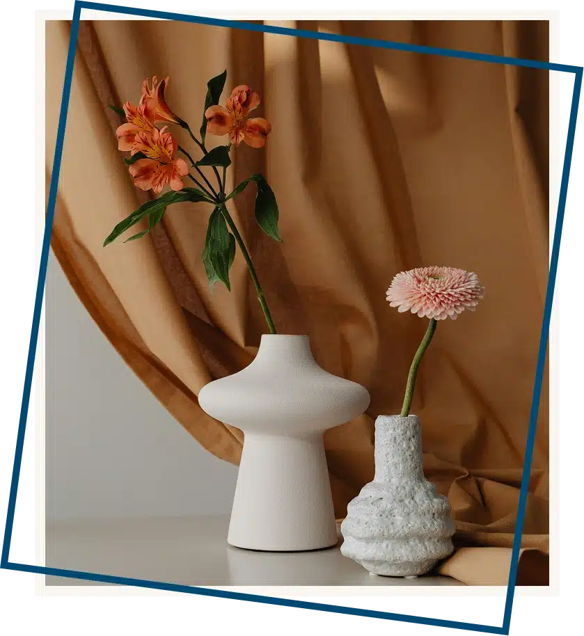 Simple flower arrangement placed before a rust-colored curtain, textured backdrop creating warmth and grounded contrast