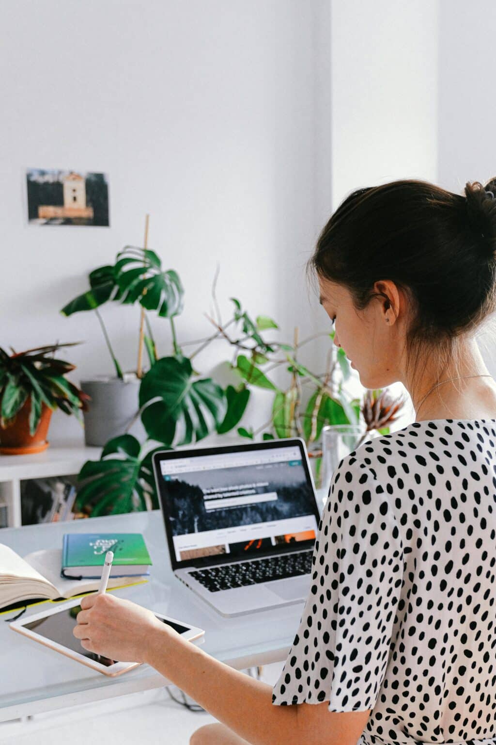 Woman sitting at a desk working on a laptop, writing thoughtfully, capturing focus, independence, and daily functioning