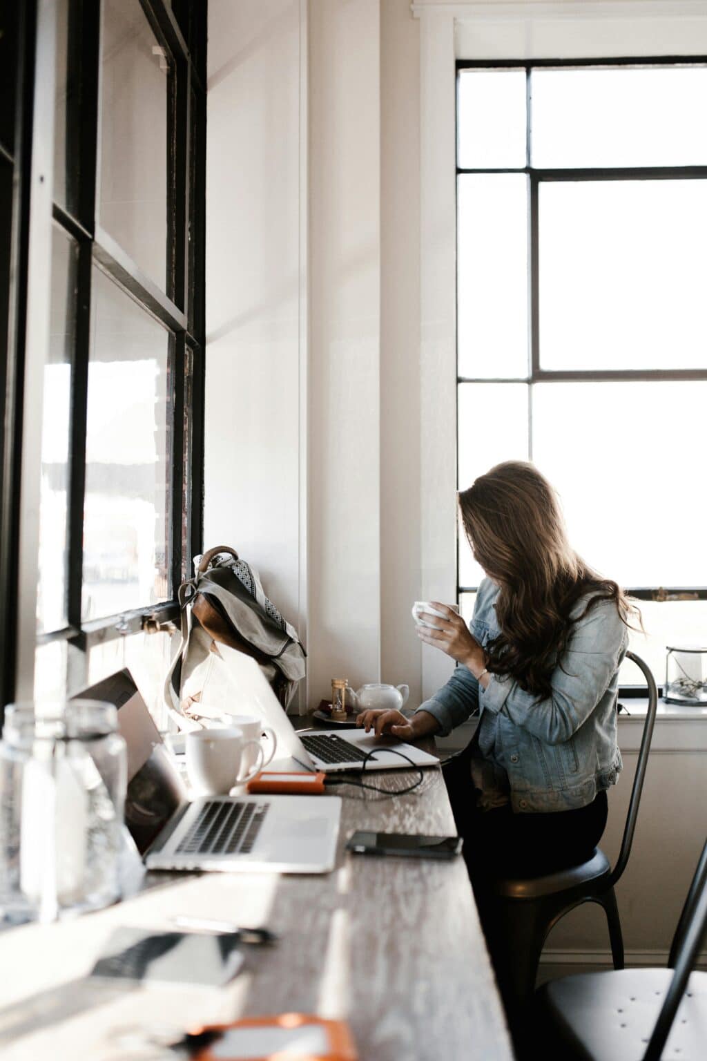 Woman working on a laptop in an office setting with coffee nearby, balanced environment suggesting focus and self-support