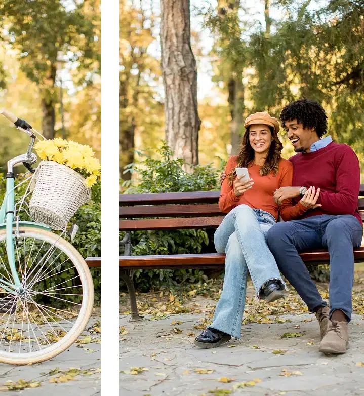 African American man and Latina woman sitting on a bench, smiling at their phones