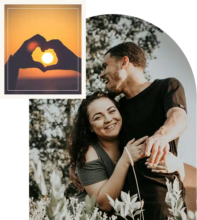 A man and woman holding each other among flowers, smiling warmly in a sunlit natural setting