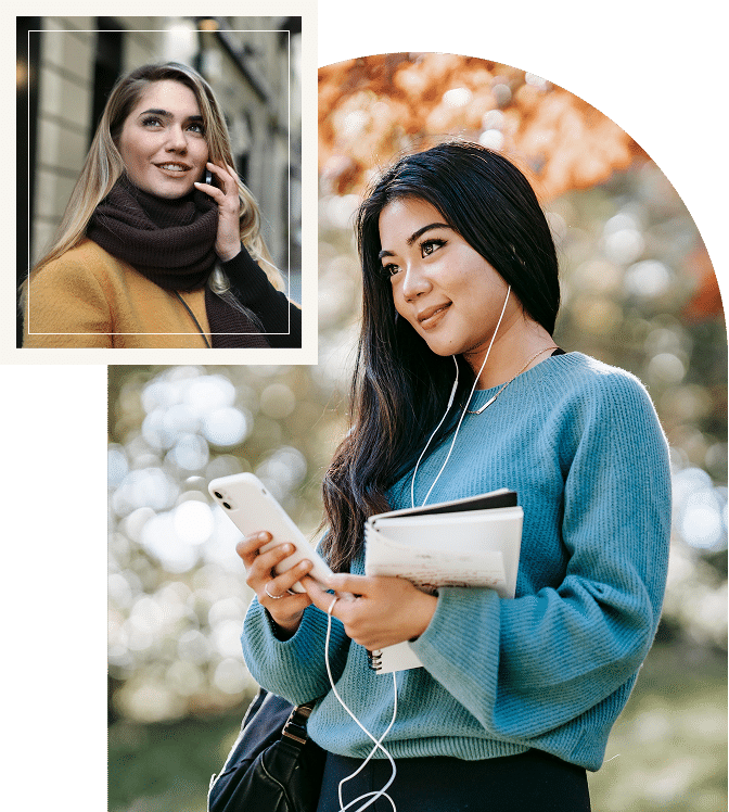 Two women smiling while talking while using mobile phone