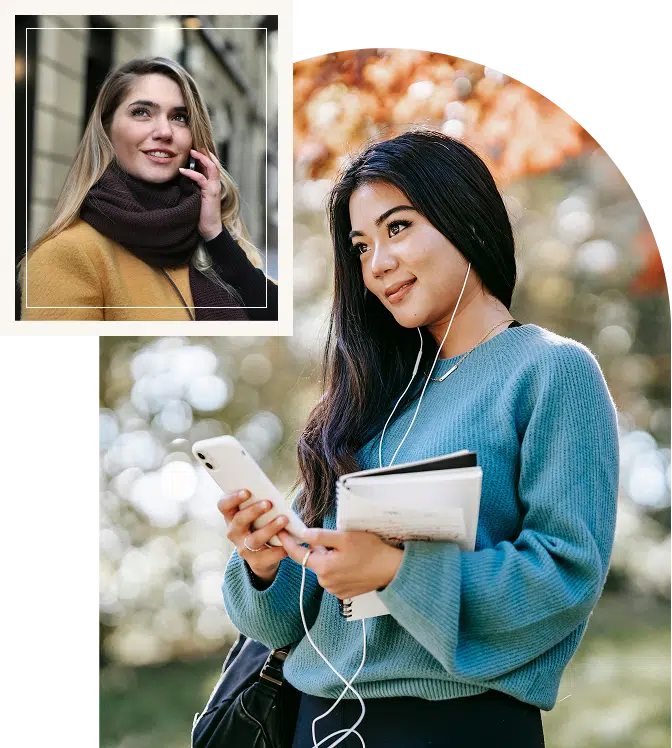 Two women smiling while talking while using mobile phone