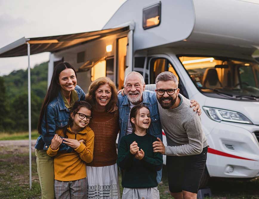 Grandparents, parents, and two kids hugging and smiling together outside their family home, sharing love across generations