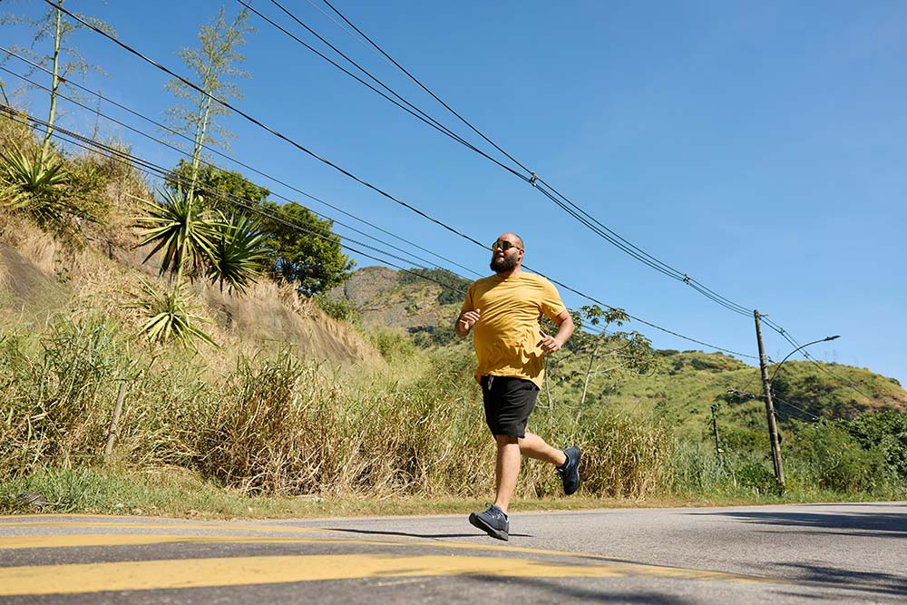 An African American man running outdoors, moving with energy and focus