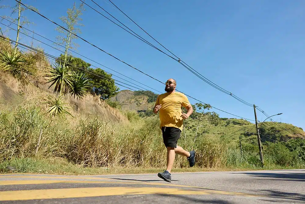 An African American man running outdoors, moving with energy and focus
