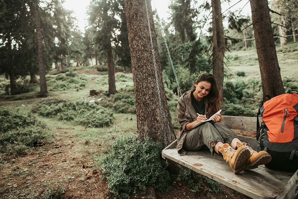 A girl on a swing in a forest, surrounded by trees and soft natural light