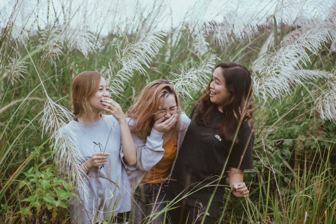 Three women laughing together outdoors, representing connection and shared experiences in group therapy