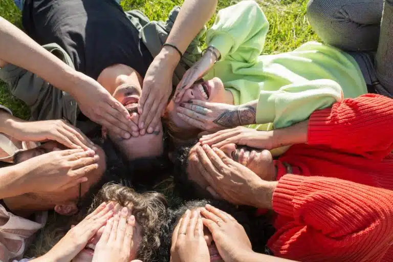 Diverse group lying in a circle laughing and bonding, symbolizing trust and connection in group therapy