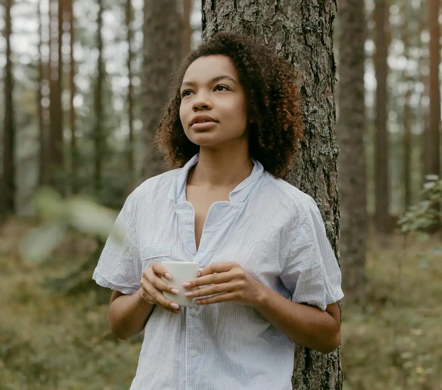  An African American woman holding coffee in a forest