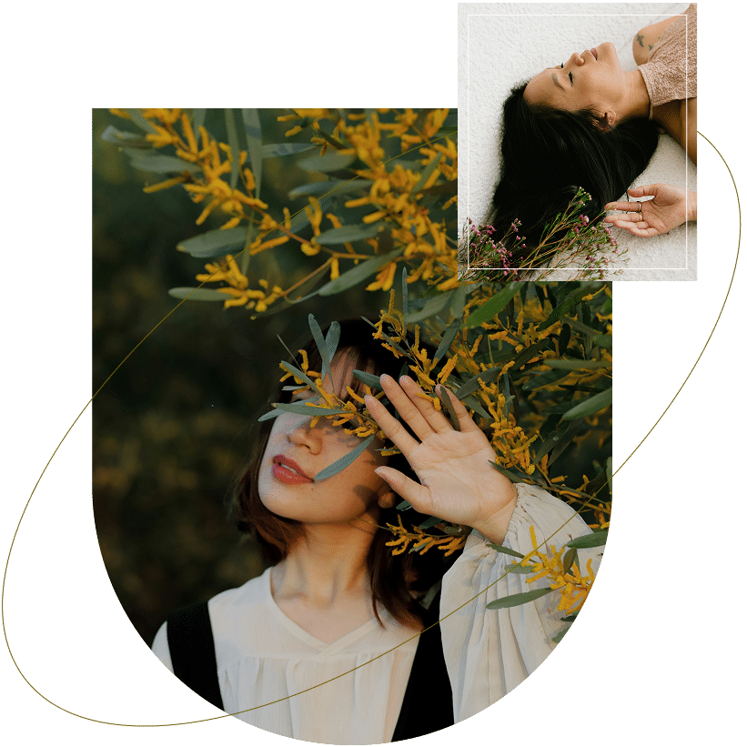 A woman stands among yellow flowering branches, gently shielding her eyes from the sunlight with her hand
