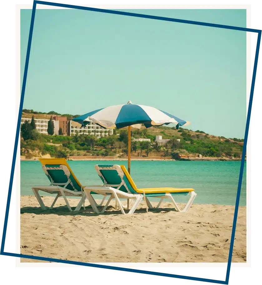 a couple of lawn chairs sitting on top of a sandy beach