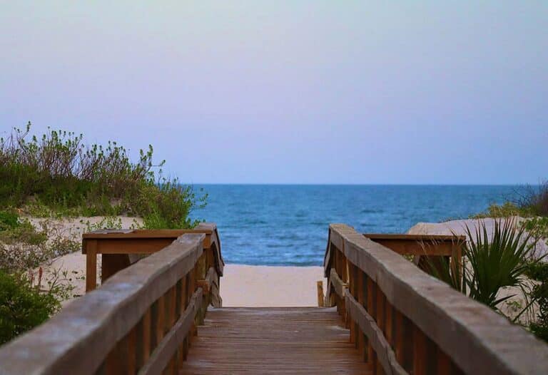 a wooden walkway leading to a beach with the ocean